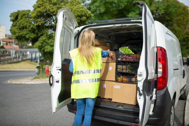 A Woman Wearing Vest Getting the Boxes at the Back of the Car